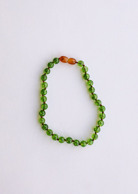 Round bead gemstone bracelet featuring green peridot stones and amber orange spacer beads