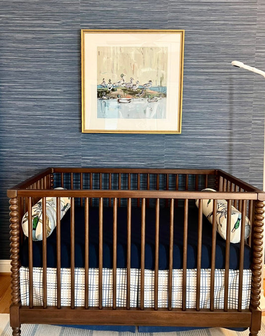 Duck-themed fine art print in gold frame, small white mat, wall and crib in view.