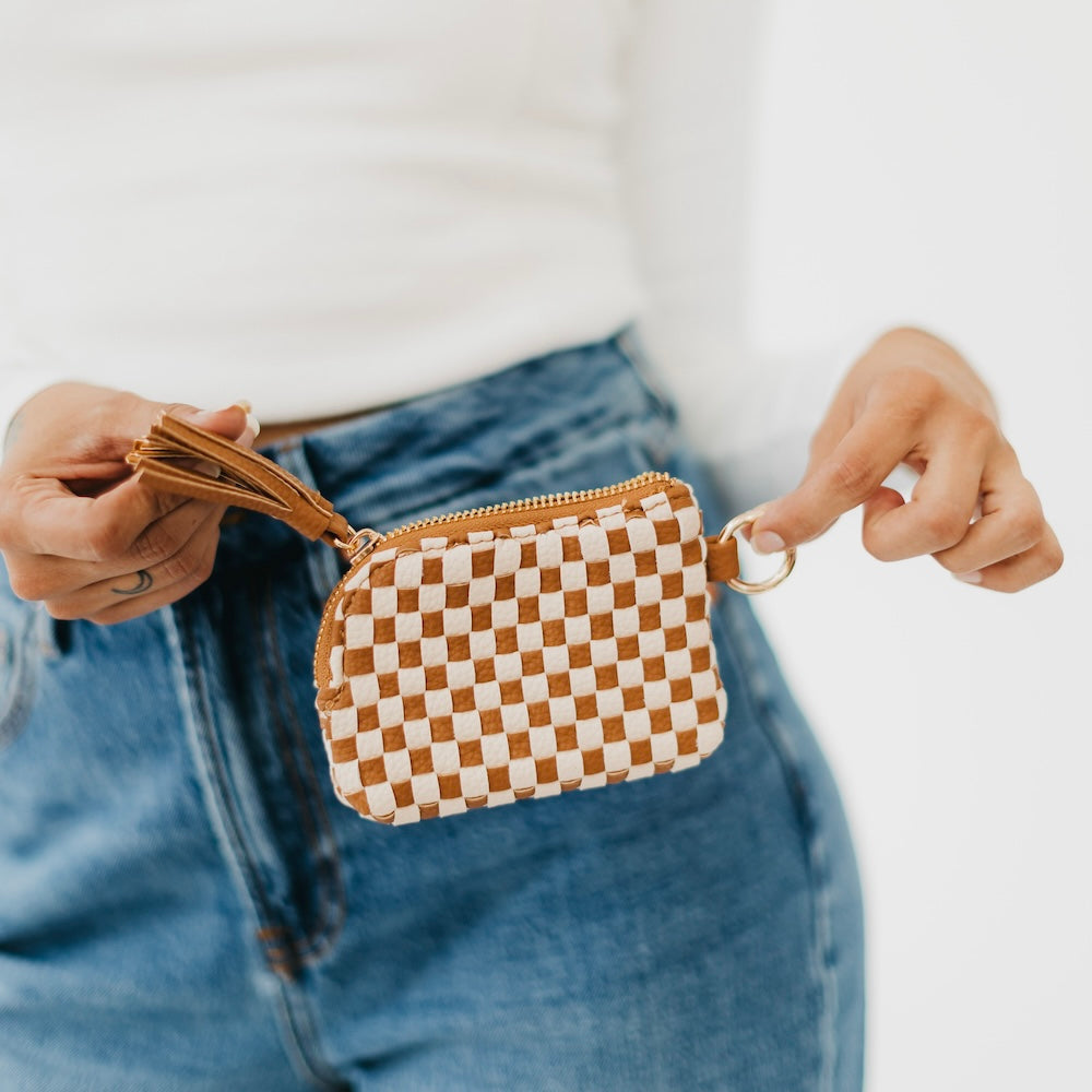 Brown checkered mini card wallet with zip top and tassel, carried in hands