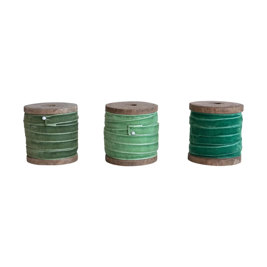 Velvet ribbon rolls on rustic wood spools in green shades