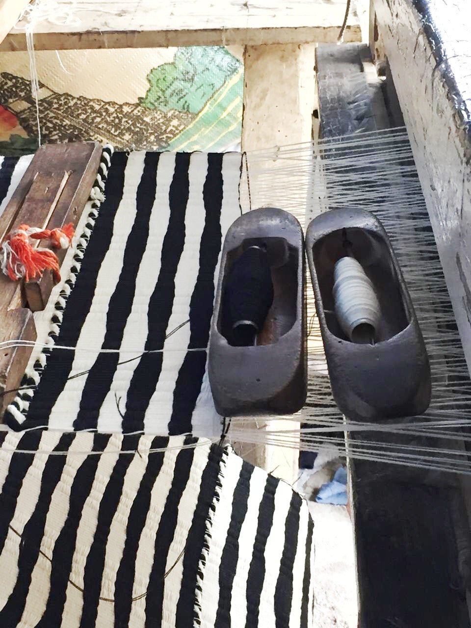 Striped fabric rug with dark slip-on shoes on top