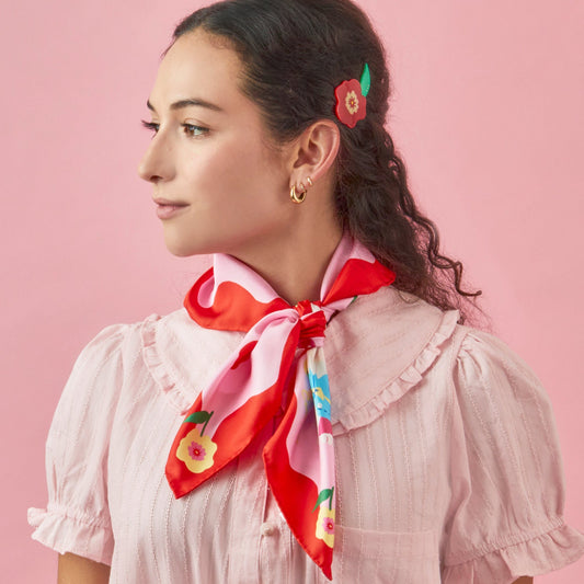 Silk square scarf tied at neck, red and pink with colorful fruit and flower print