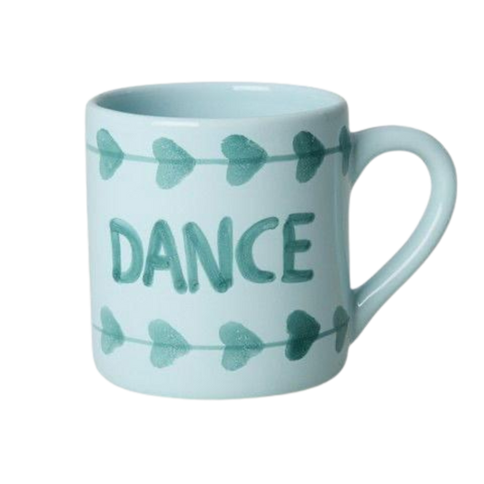 Light blue ceramic mug with green hand-painted DANCE text and bow-shaped accents
