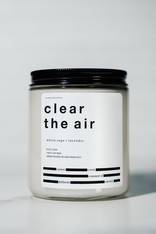White candle jar with black lid and bold clear the air label, white sage lavender