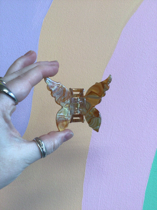 Butterfly hair claw with amber-gold iridescent wings and metal hinged clip
