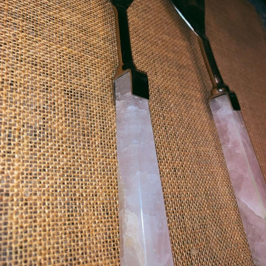 Two rose quartz serving spoons with long pink stone handles and metal ends