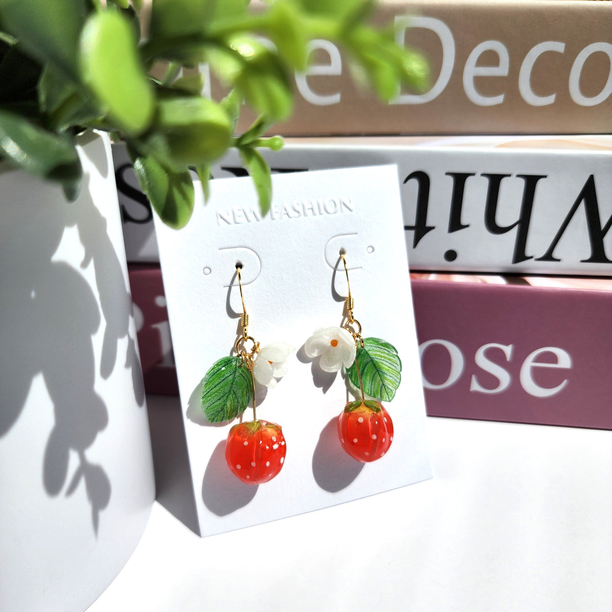 Strawberry flower resin earrings shown on a retail card with white blossoms and red berries