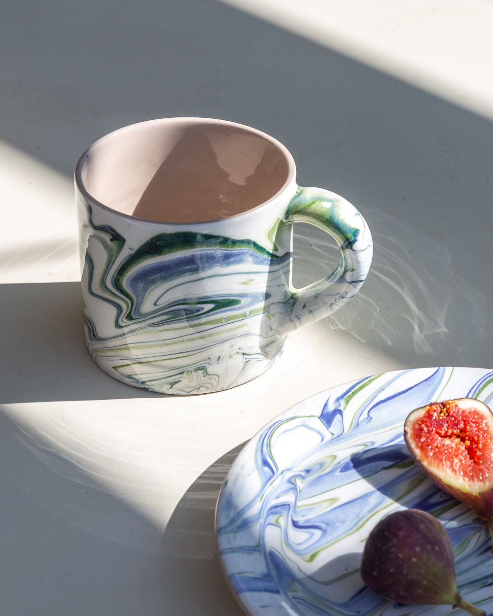 Marbled ocean ceramic mug, green and blue swirls with visible interior in warm tan