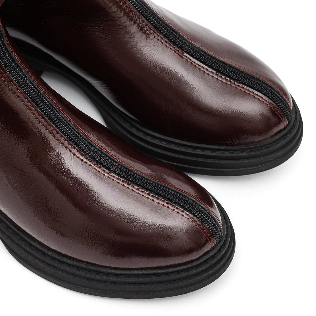 Close-up of the burgundy leather boots' rounded toes and front zippers