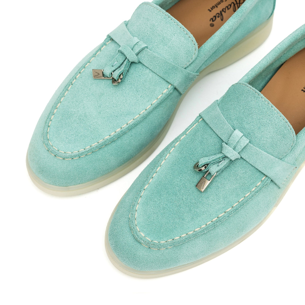 Close-up of turquoise suede loafers with apron stitching and metal bit accents