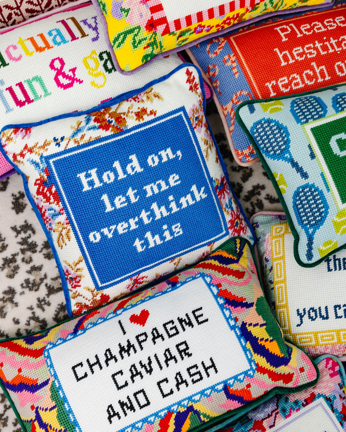 Needlepoint pillow with blue center panel and "overthink this" text, bordered in floral pattern