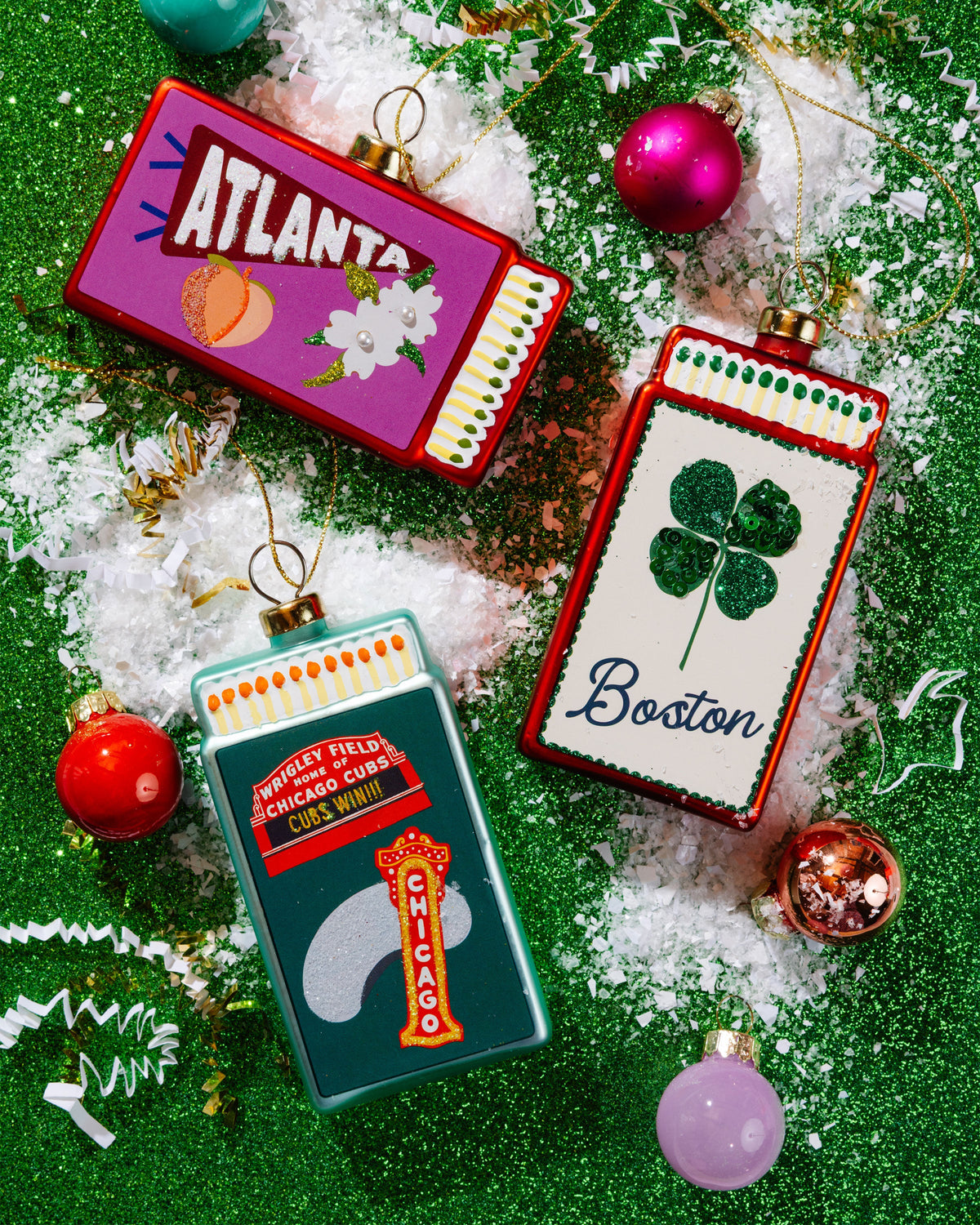 Assorted matchbook ornaments on green tinsel, including a Chicago Cubs design