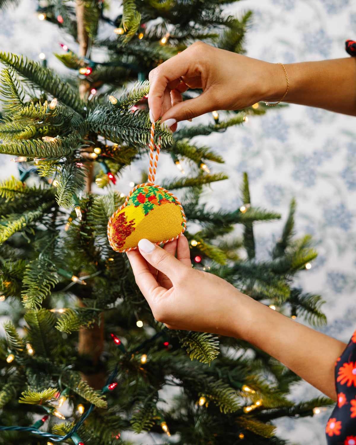 Needlepoint taco ornament hanging from a Christmas tree branch