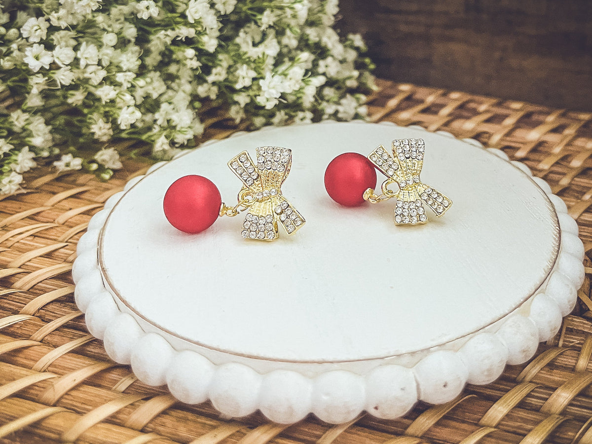 Gold bow Christmas bulb ornaments on white plate with red bead drops and rhinestones