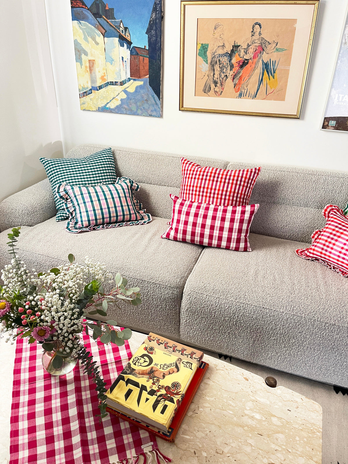 Red and multicolor plaid ruffle pillow on a sofa with decorative accents nearby
