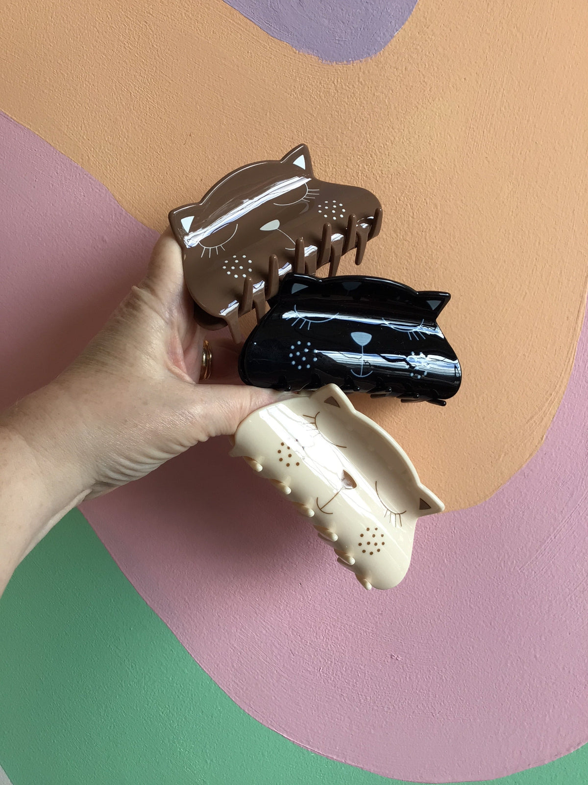 Set of three kitty hair claw clips: brown, black, and cream with cartoon faces