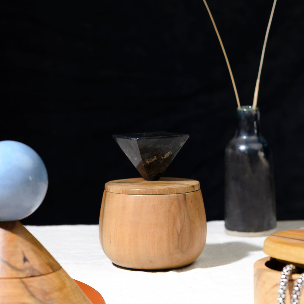 Round wooden jewel box with black triangular lid on top