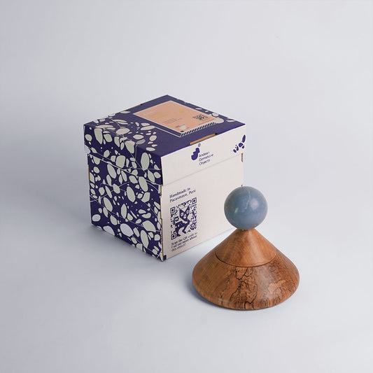 Incense cone holder with blue sphere and wooden base beside patterned gift box
