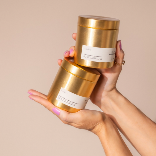 Amber sandalwood 9 oz candle, gold jar held in hands with matching lid