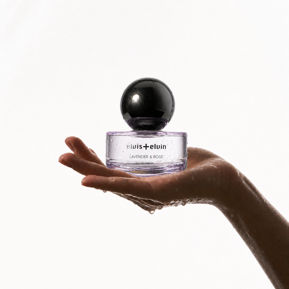 Lavender & Rose perfume bottle held in open palms with black cap and purple glass