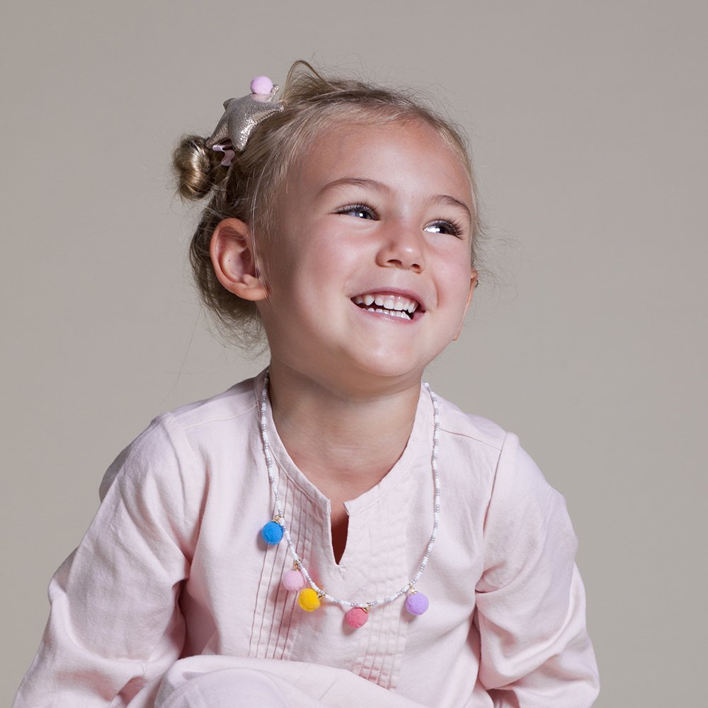 Girls' colorful pompom necklace worn with a pale pink top