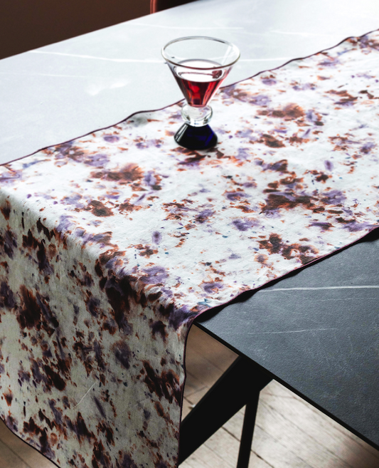 Marble-pattern table runner draped over table edge, white base with brown rose speckles