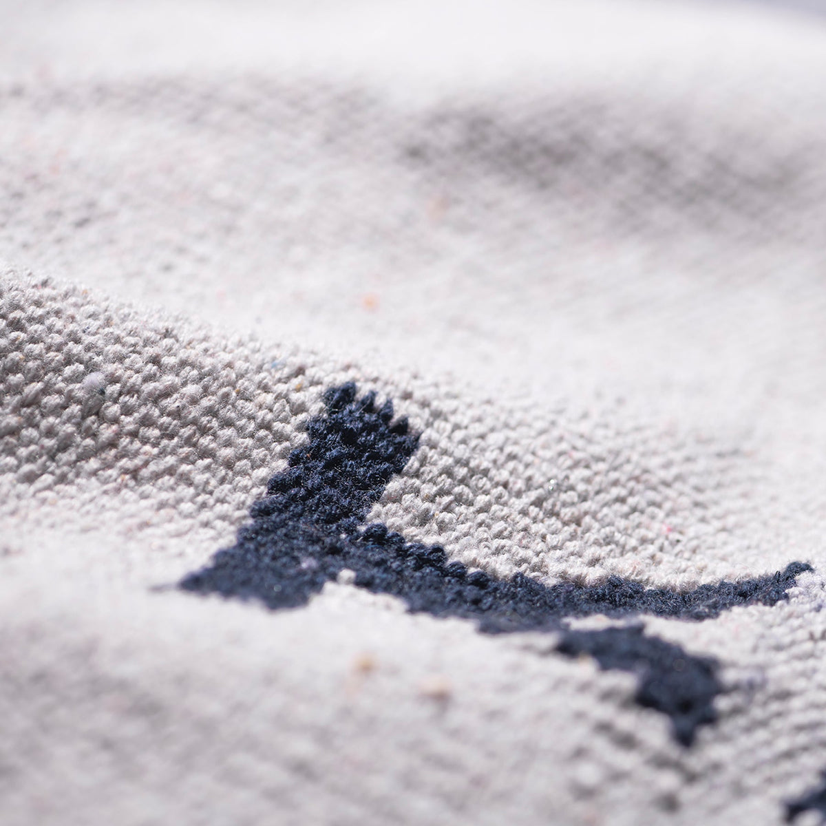 Close-up of light kitchen mat fabric with navy yarn stitching