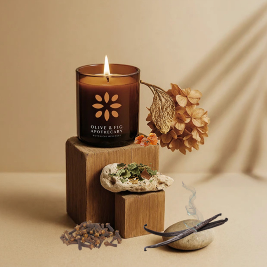 Burning amber glass candle with botanical flower emblem on the front