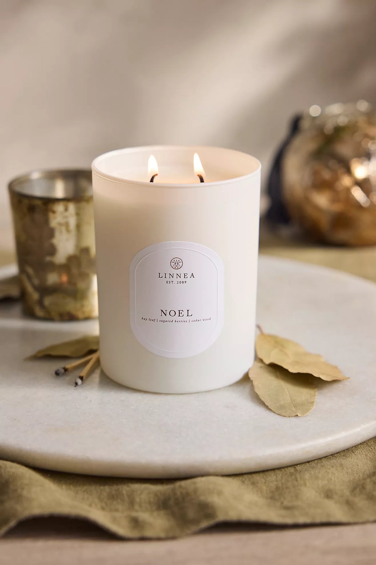 Large white 2-wick candle with Noel label and two lit flames