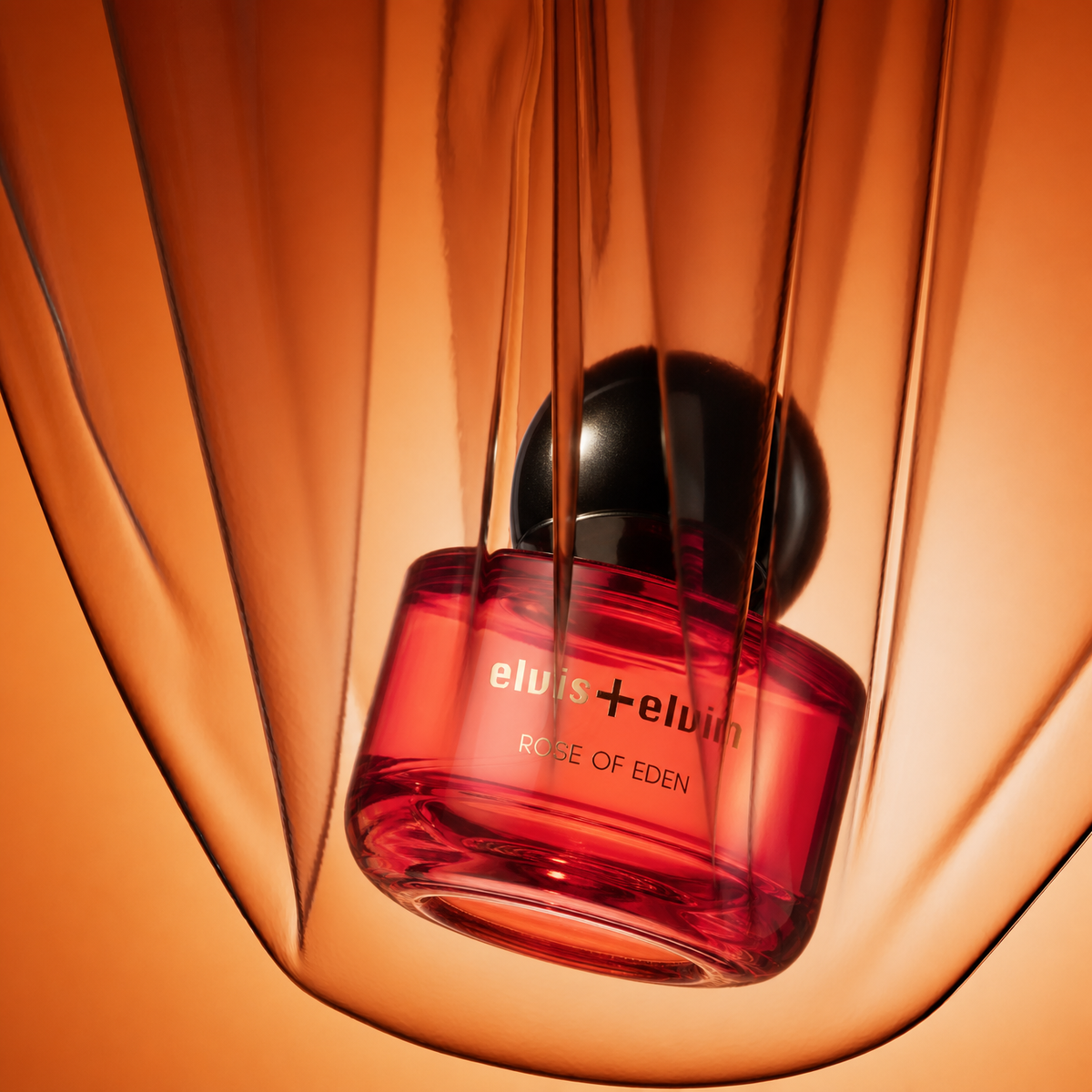 Rose of Eden perfume bottle, red glass with black cap, angled view
