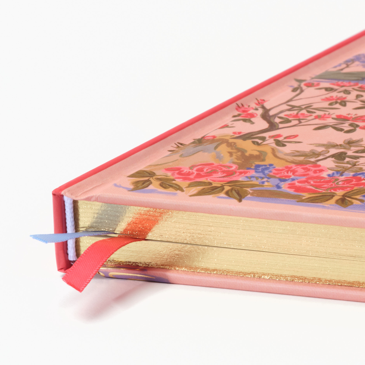 Hardcover notebook spine close-up with pink ribbon and gold-edged pages