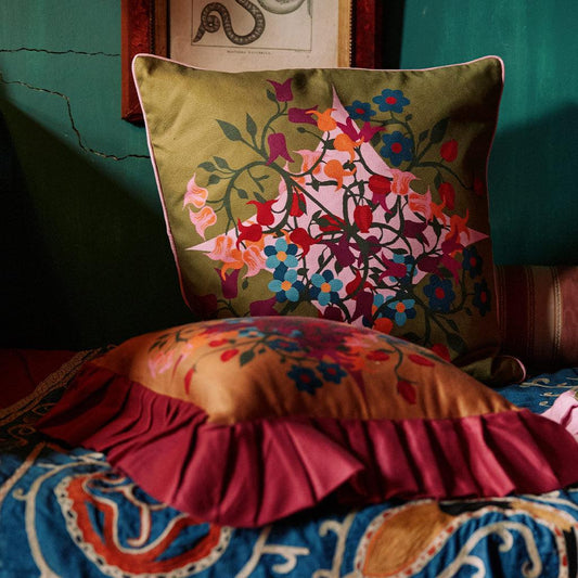 Square green pillow cover with vibrant floral pattern and dark edge piping