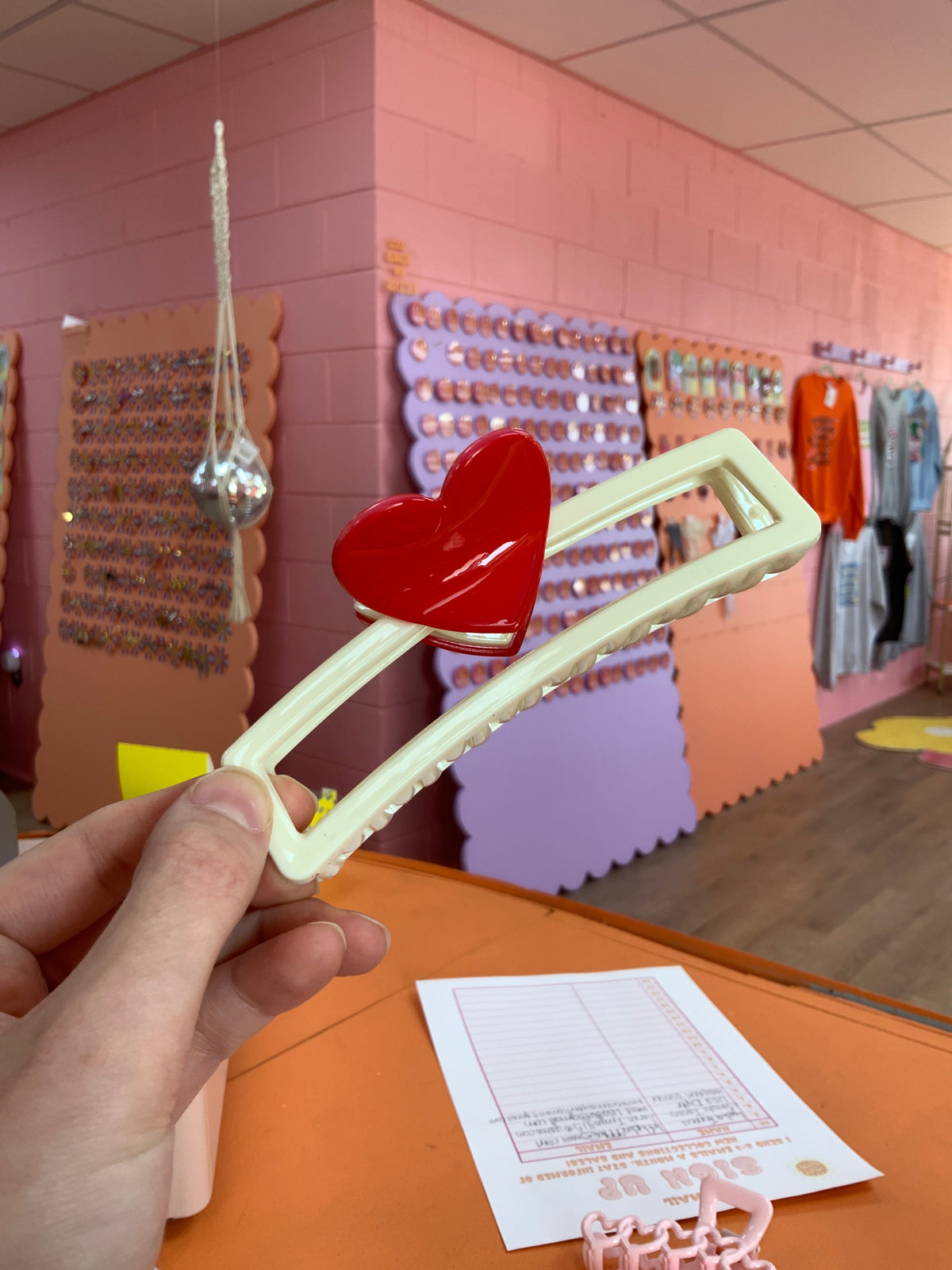 Cream hair claw with red heart top and interlocking heart-shaped links.