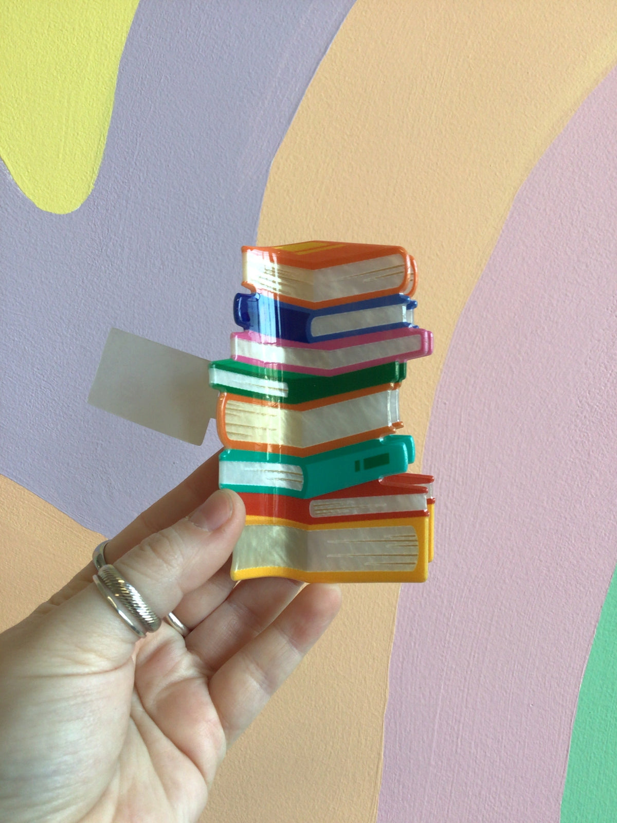 Book stack hair claw with stacked mini-book tiers in teal, orange, and yellow