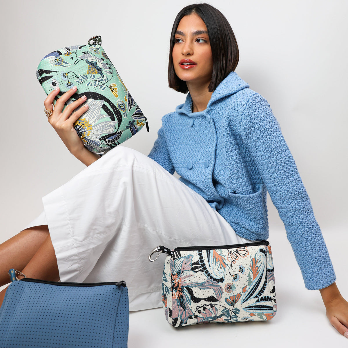 Zippered canvas pouch with pastel blossom print, held with a black strap