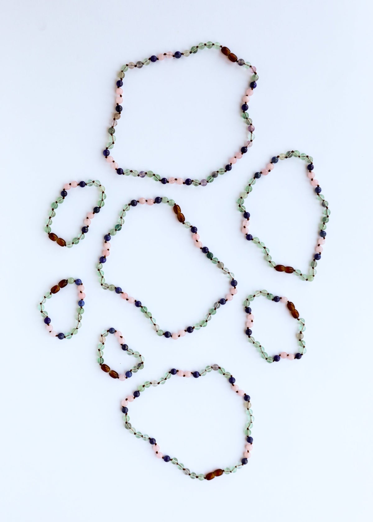Set of five beaded gemstone bracelets with green, pink, and dark blue beads
