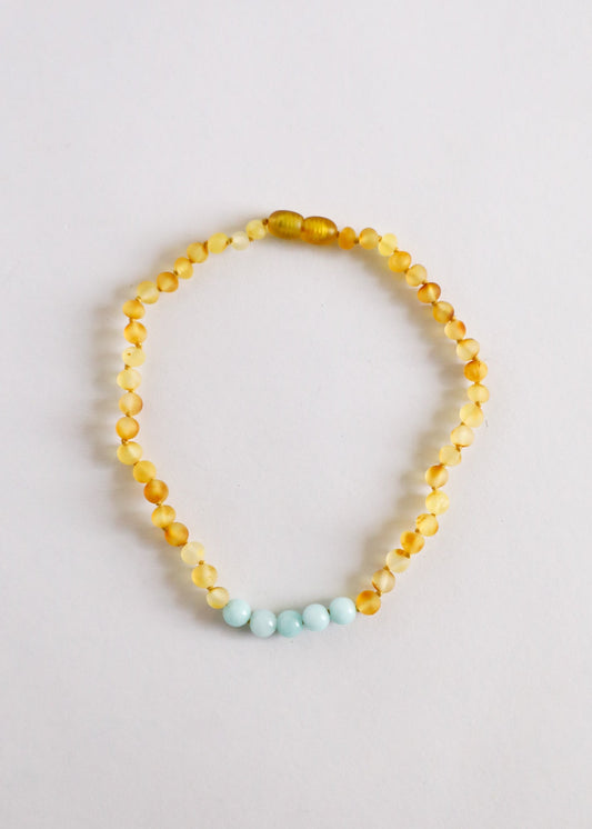 Gold-toned beaded necklace with light blue accent beads in a teardrop strand