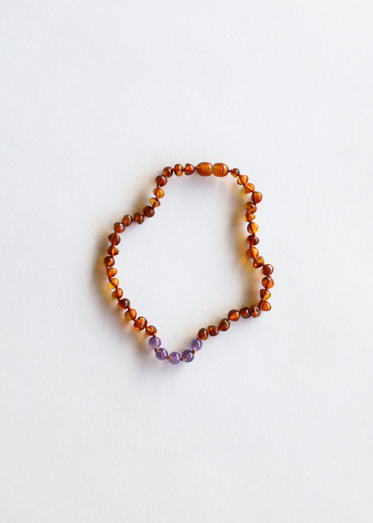 Amber bead necklace with small purple amethyst accents, laid flat