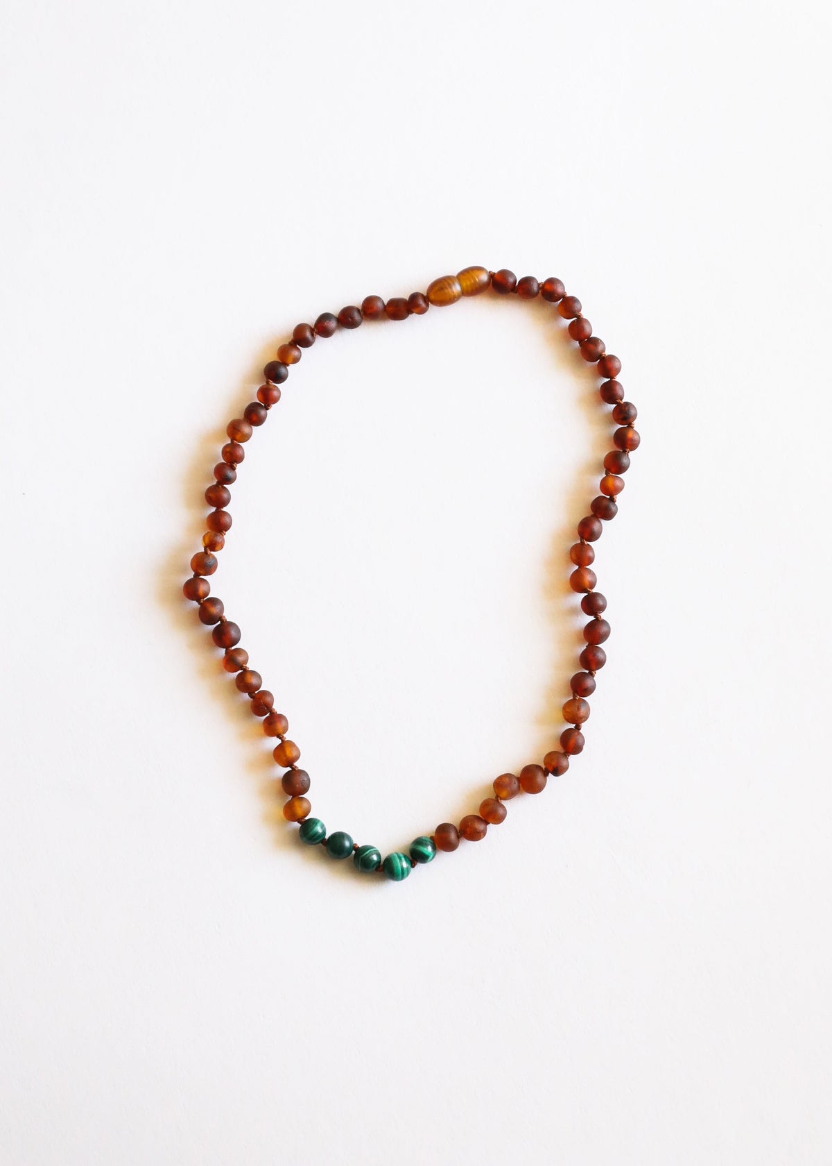 Amber bead necklace with green malachite bead at bottom center