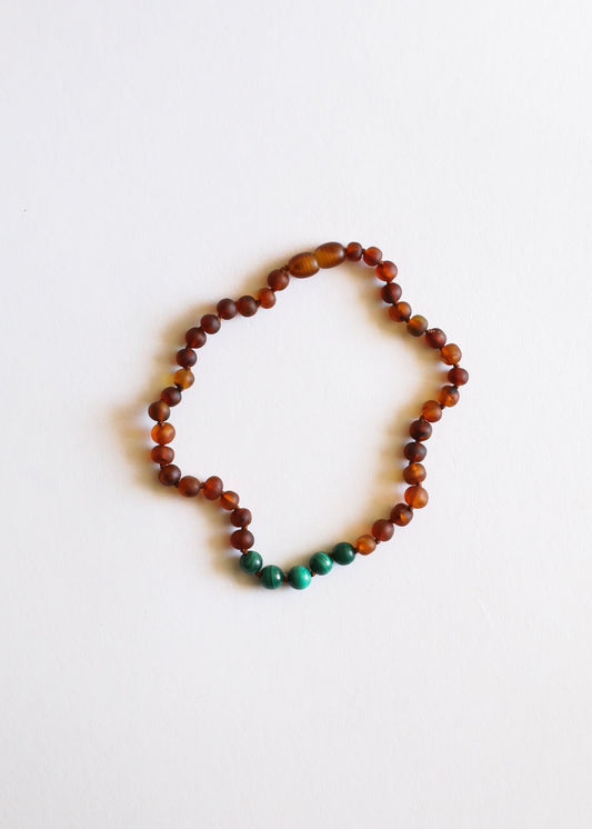 Amber bead necklace with small green accent beads at bottom
