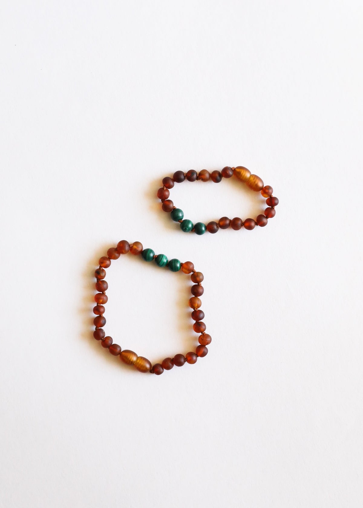 Two amber and malachite bead bracelets, round cognac beads with green accents