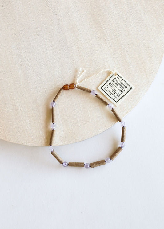 Beaded necklace with clasp and small tag; light brown beads, lavender accents, amber bead