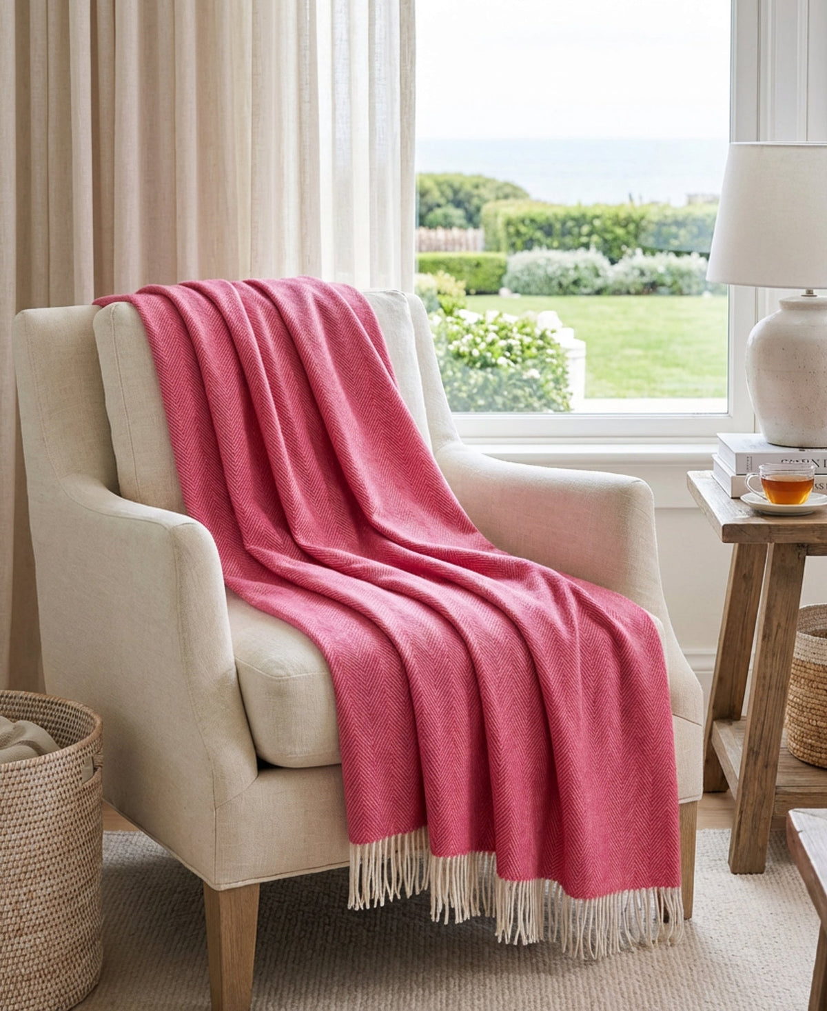 Pink herringbone lambswool throw draped on armchair with fringed edge