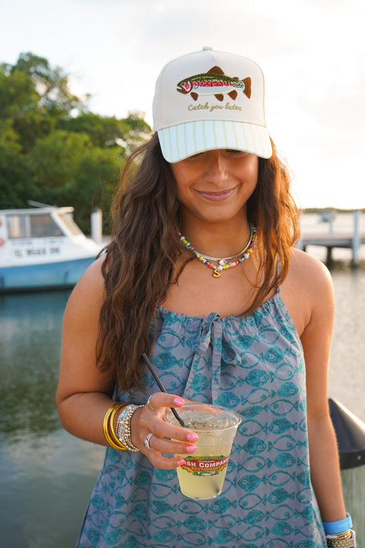 White fish-embroidered cap worn with blue patterned dress, mint striped brim