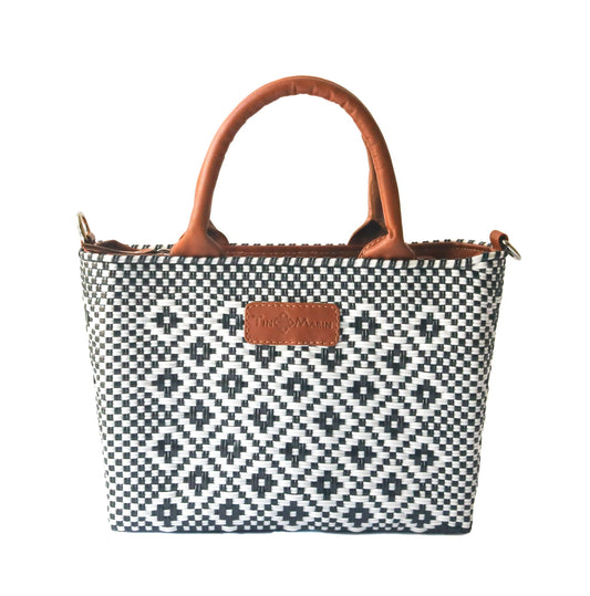 Small woven crossbody bag, black-and-white weave with tan leather handles and logo patch.