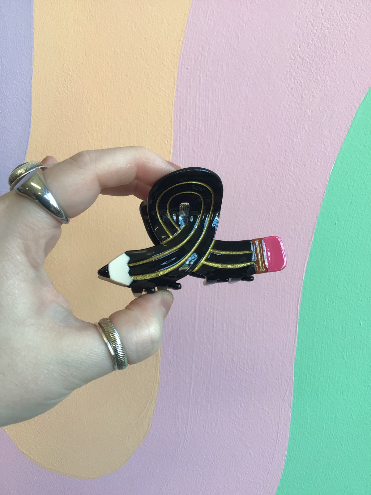 Black cartoon-style hair claw with yellow stripes and pink accent.