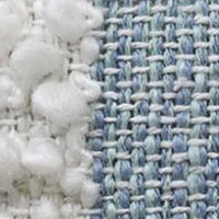 Close-up of light blue woven fabric with cream pom-pom trim along the edge