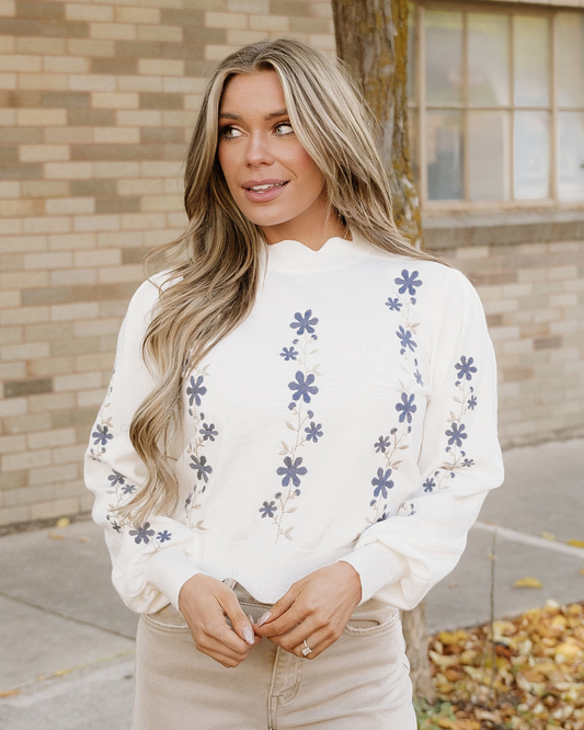 White cropped sweater with long sleeves and blue flower embroidery
