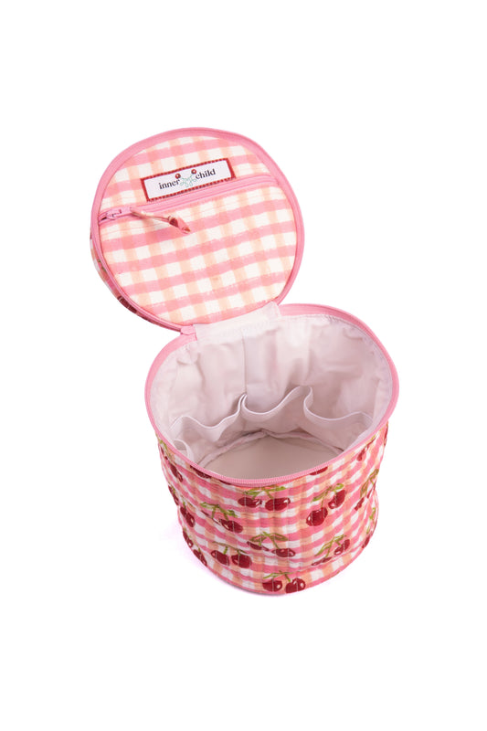 Upright round makeup bag opened, showing pink gingham cherry print interior