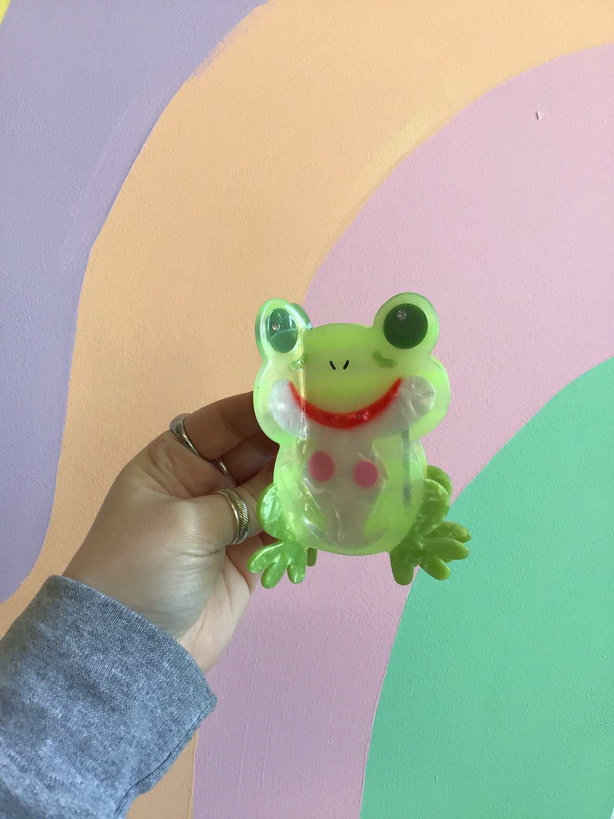 Green frog hair claw with bulging eyes, smiling face, and clear pink detail.